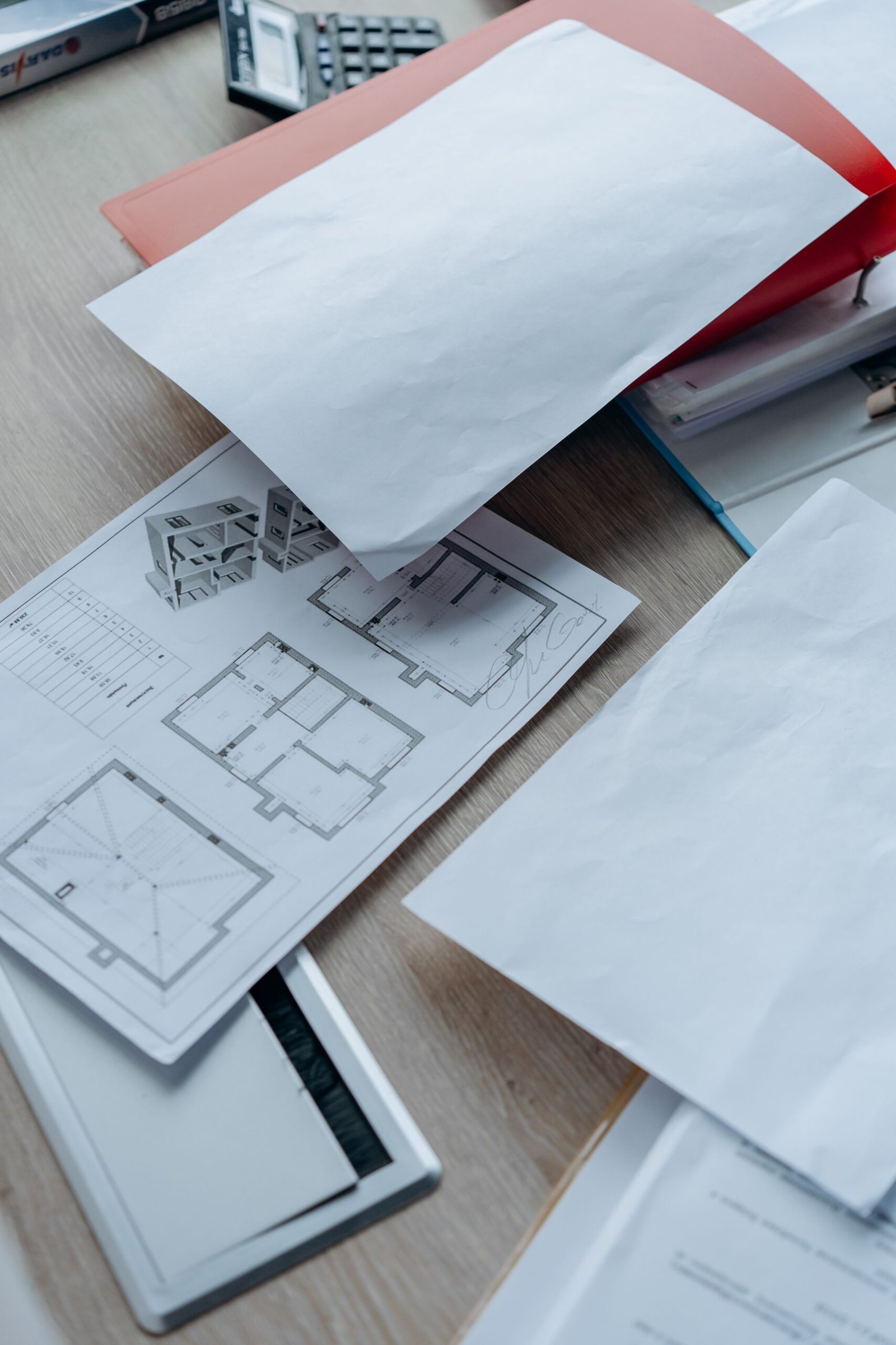 Calculadora, planos de reforma y presupuesto de obra sobre una mesa